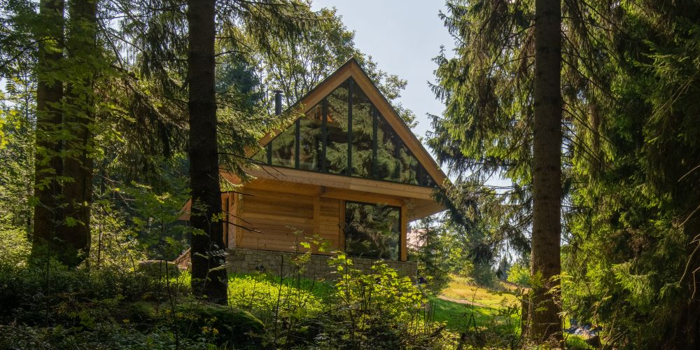 Zpustošenou chatu na kraji lesa nahradili moderní víkendovou dřevostavbou, kde společně tráví volný čas